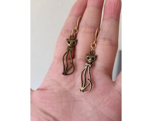 Brown cat earrings. Each cat is wearing a cute bow tie. They are attached to muted gold jump rings and ear wires.